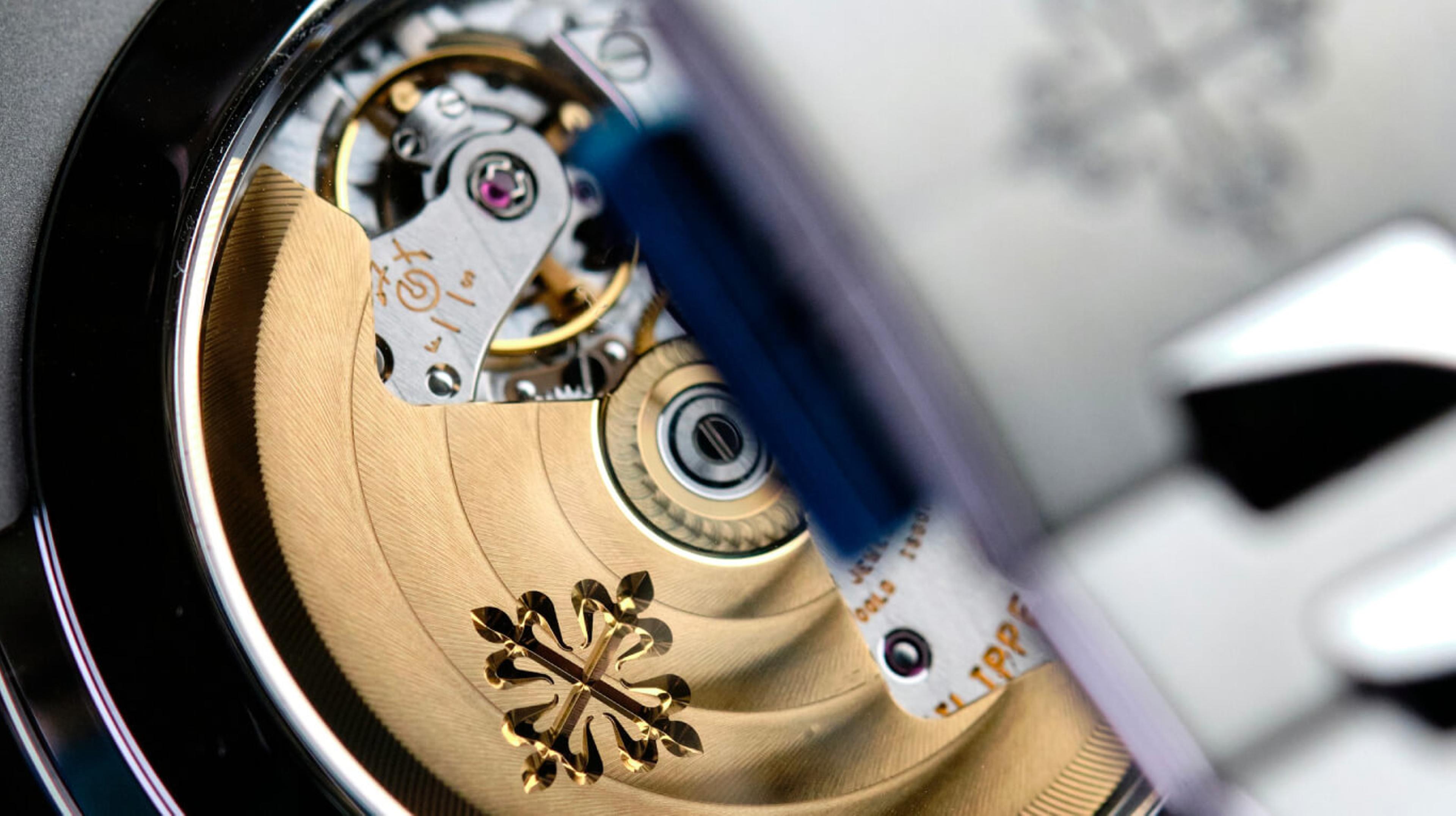 Back of automatic watch showing balance wheel, and rotor with Patek Phillipe logo on it in gold