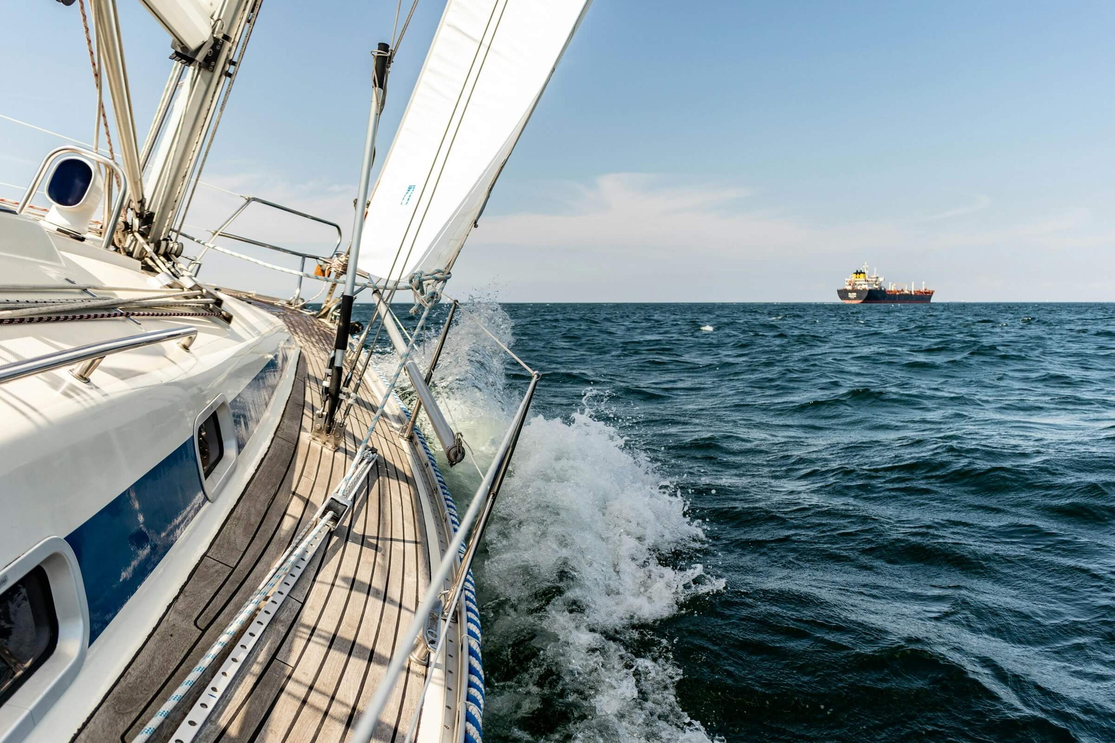 Sailing yacht tilting to left in ocean water going toward the horizon